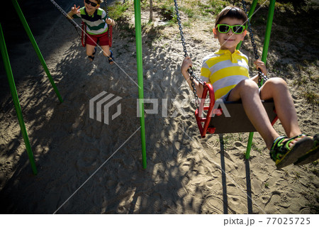 European boy on chain swing. Summer leisure time concept 77025725