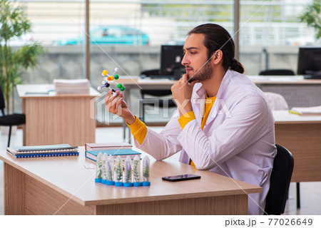 Young male chemist in drug synthesis concept 77026649