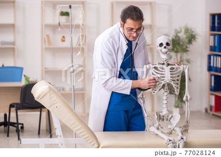 Young male doctor and skeleton patient in the clinic Young male doctor and skeleton patient in the clinic 77028124