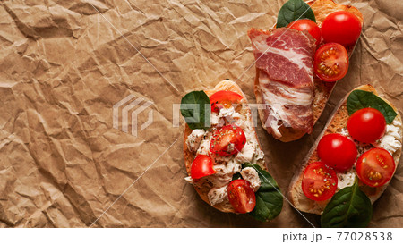 Three fresh bruschetta on craft paper. Delicious snack. View from above Three fresh bruschetta on craft paper. Delicious snack. View from above 77028538