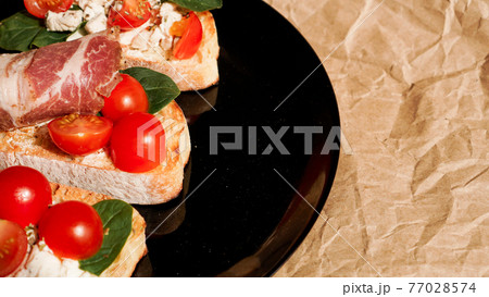 Three bruschetta on a black plate on craft paper 77028574