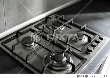 Stainless grey metal kitchen gas stove installed on a the kitchen with a dark grey table top. Stainless grey metal kitchen gas stove installed on a the kitchen with a dark grey table top. 77028914