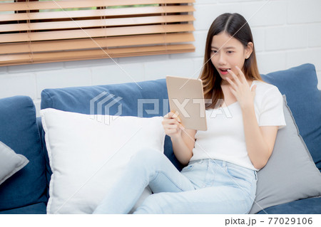 Young attractive asian woman resting using browsing tablet computer on sofa at home. Young attractive asian woman resting using browsing tablet computer on sofa at home. 77029106