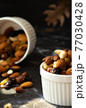 Mix of delicious assorted nuts and dried fruit in white cups on a table, sunny morning. Healthy gourmet vegetarian natural snack. 77030428