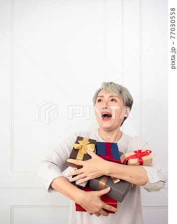 Senior asian woman holding mount of gift boxes, enjoying many best presents. 77030558