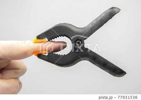 black plastic clothespin hanging on your finger 77031536