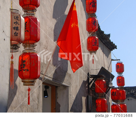 Hongcun Ancient Town in Anhui Province, China. Exterior of traditional building with red lanterns and Chinese flag in Hongcun. Historic architecture of the ancient town of Hongcun in China Hongcun Ancient Town in Anhui Province, China. Exterior of traditional building with red lanterns and Chinese flag in Hongcun. Historic architecture of the ancient town of Hongcun in China 77031688