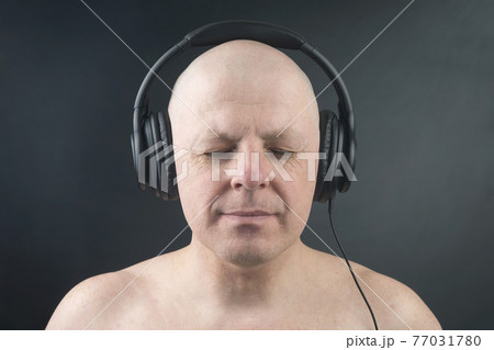 man with closed eyes listens to music with headphones on dark background man with closed eyes listens to music with headphones on dark background 77031780