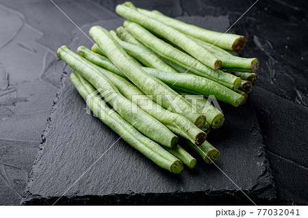Green french beans cooking, on stone board, on black background Green french beans cooking, on stone board, on black background 77032041