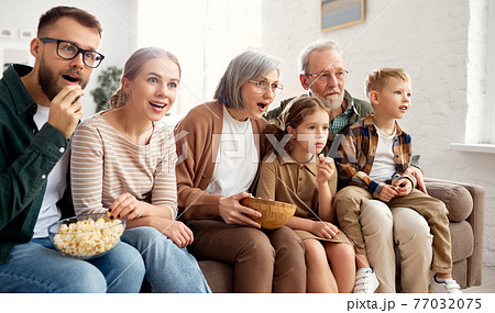 Happy big family watching TV and eating popcorn Happy big family watching TV and eating popcorn 77032075