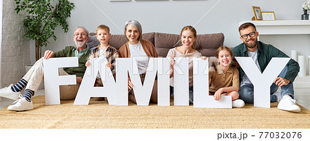 Big family holding word FAMILY and looking at camera while sitting on floor near sofa Big family holding word FAMILY and looking at camera while sitting on floor near sofa 77032076