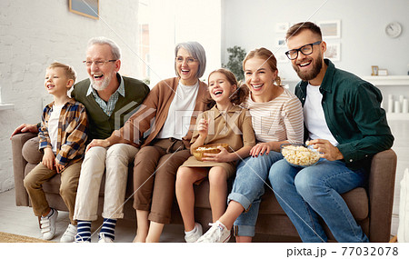 Happy big family watching TV and eating popcorn 77032078