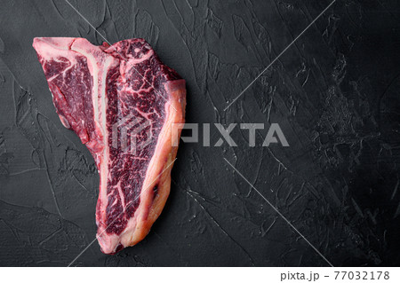 Dry aged t bone marbled beef steak, on black stone background, top view flat lay, with copy space for text Dry aged t bone marbled beef steak, on black stone background, top view flat lay, with copy space for text 77032178