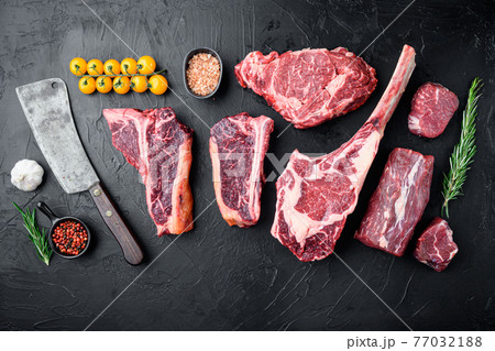 Various cuts of marbled beef meat and dry aged steaks, tomahawk, t bone, club steak, rib eye and tenderloin cuts, on black stone background, top view flat lay, with copy space for text Various cuts of marbled beef meat and dry aged steaks, tomahawk, t bone, club steak, rib eye and tenderloin cuts, on black stone background, top view flat lay, with copy space for text 77032188