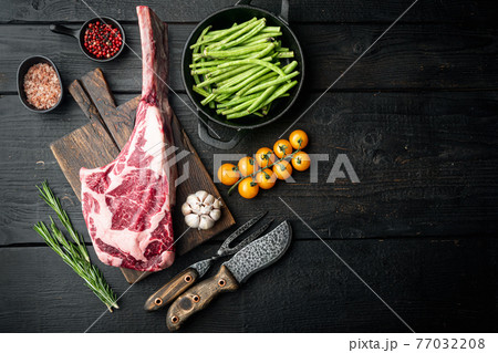 Organic marbled beef meat Steak and seasonings, Tomahawk cut, on wooden cutting board, on black wooden table background, top view flat lay, with copy space for text Organic marbled beef meat Steak and seasonings, Tomahawk cut, on wooden cutting board, on black wooden table background, top view flat lay, with copy space for text 77032208