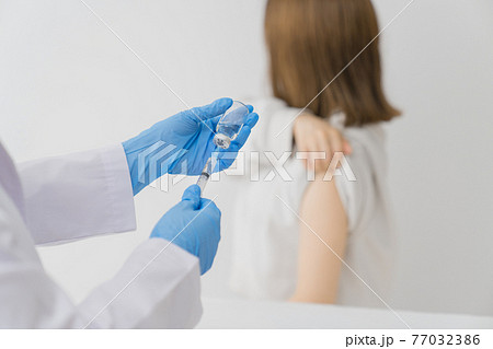 バイアルからワクチンを引く医者 77032386