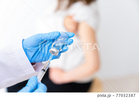 バイアルからワクチンを引く医者 77032387