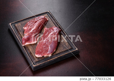 Raw duck breast with herbs and spices on a dark concrete background Raw duck breast with herbs and spices on a dark concrete background 77033126