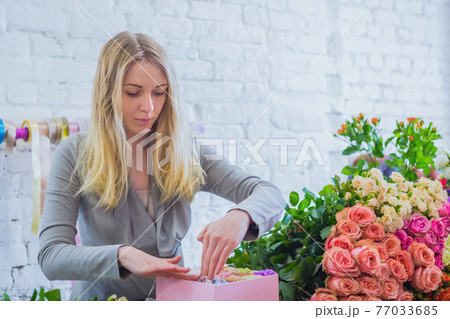 Professional florist making gift box with flowers at flower store 77033685