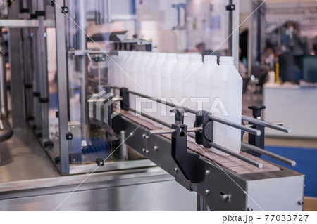 White bottles on conveyor belt of liquid filling machine White bottles on conveyor belt of liquid filling machine 77033727