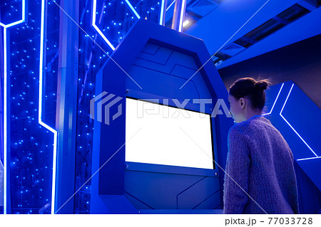 Woman looking at blank white display kiosk at exhibition - white screen concept Woman looking at blank white display kiosk at exhibition - white screen concept 77033728