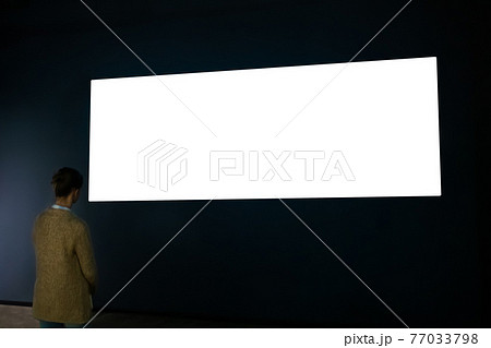 Woman looking at blank wide interactive wall display - white screen concept Woman looking at blank wide interactive wall display - white screen concept 77033798