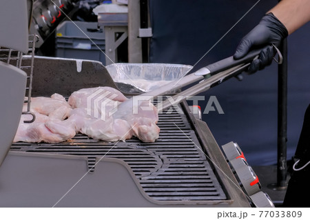 Chef preparing chicken meat for grilling at street food festival - close up view Chef preparing chicken meat for grilling at street food festival - close up view 77033809