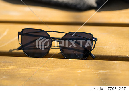Cat eye sunglasses special design with black lenses and black frame for ladies shoot in a summer day. Selective focus  77034267