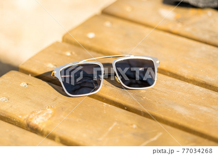 Oversized sunglasses design with big black flat lenses closeup shoot outside in a summer day . Selective focus 77034268