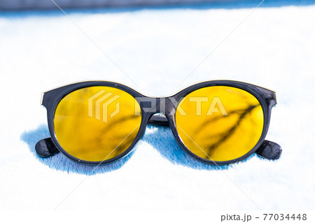 Fashion cat eye sunglasses for ladies with big round yellow lenses and black frame shoot outside in a sunny day closeup. Selective focus  77034448