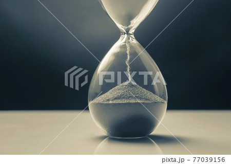 Hourglass on a dark background. Time is money. Business solutions in time. Hourglass on a dark background. Time is money. Business solutions in time. 77039156
