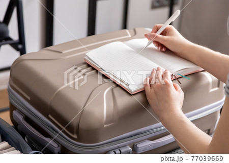 Closeup female hands writing paper notes making list of necessary things to travel trip vacation Closeup female hands writing paper notes making list of necessary things to travel trip vacation 77039669