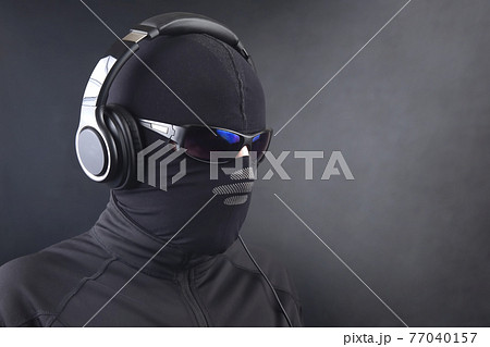 portrait of a man in a black mask and sunglasses listening to music on headphones 77040157
