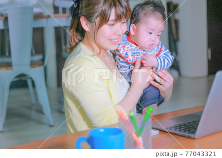 _テレワークの母親とPCに興味を示す乳児1 77043321