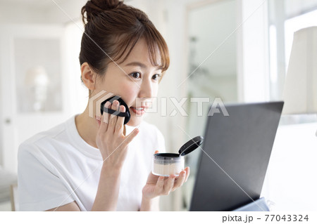 お化粧をするかわいい女性 77043324