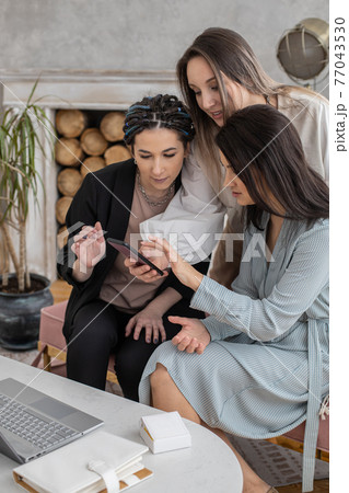 Group happy female friends chatting surfing internet use smartphone smiling having positive emotion Group happy female friends chatting surfing internet use smartphone smiling having positive emotion 77043530