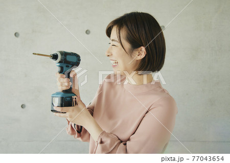 Young Woman Holding Electric Screwdriver 77043654