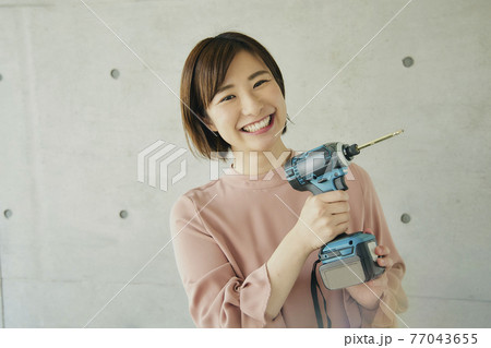 Young Woman Holding Electric Screwdriver 77043655