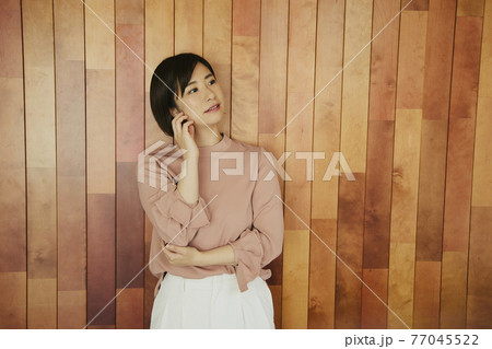 Woman standing by wooden wall 77045522