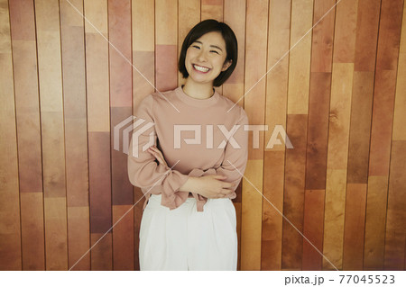 Woman standing by wooden wall 77045523