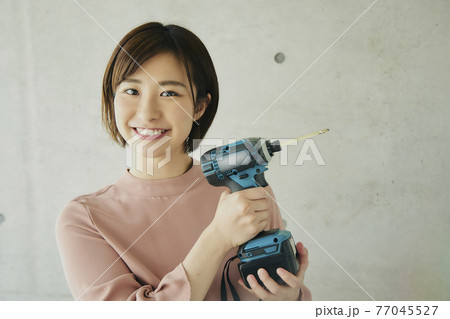 Young Woman Holding Electric Screwdriver 77045527