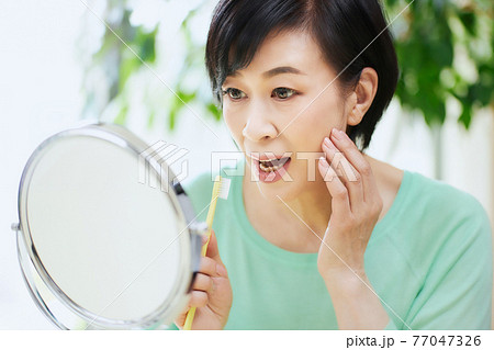 歯ブラシを持つミドル女性　歯痛 77047326