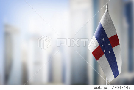 A small flag of Netherlands Antilles on the background of a blurred background 77047447