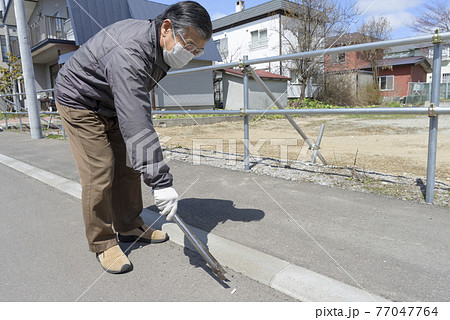 吸い殻を拾うシニア男性 吸い殻を拾うシニア男性 77047764