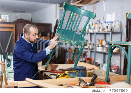 Carpenter repairing antique chair 77047869
