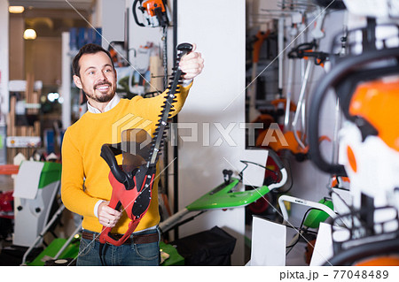 Guy looks range of hedge cutters 77048489