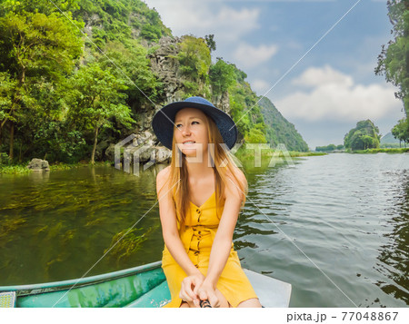 Woman tourist in boat on the lake Tam Coc, Ninh Binh, Viet nam. It's is UNESCO World Heritage Site, renowned for its boat cave tours. It's Halong Bay on land of Vietnam. Vietnam reopens borders after 77048867