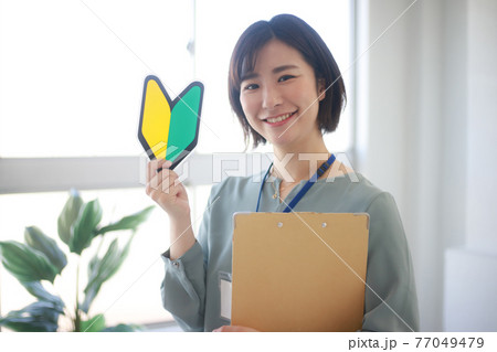 初心者マークとバインダーを持つ女性社員 初心者マークとバインダーを持つ女性社員 77049479