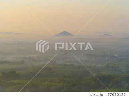 Aerial top view of forest trees with fog mist and green mountain hill at sunset. Nature landscape background, Thailand. Aerial top view of forest trees with fog mist and green mountain hill at sunset. Nature landscape background, Thailand. 77050122