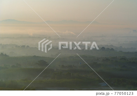 Aerial top view of forest trees with fog mist and green mountain hill at sunset. Nature landscape background, Thailand. Aerial top view of forest trees with fog mist and green mountain hill at sunset. Nature landscape background, Thailand. 77050123